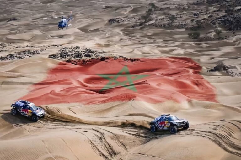 مسؤولو رالي داكار يضعون اللمسات الأخيرة مع المغرب تمهيدا لعودة الرالي إلى المملكة سيارات رالي داكار وسط الكثبان الرملية مع العلم المغرب